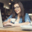 Beautiful hipster woman using laptop at cafe